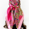 A vibrant pink scarf featuring a paisley print with leopard spots tied around a woman's hair.