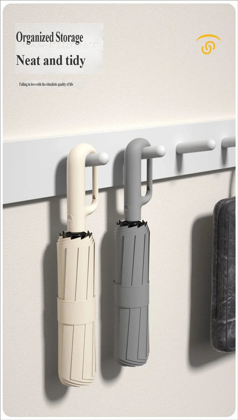 Two automatic folding umbrellas, one cream and one gray, are mounted on a wall rack.