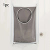 A gray fabric laundry organizer hanging on a white door.
