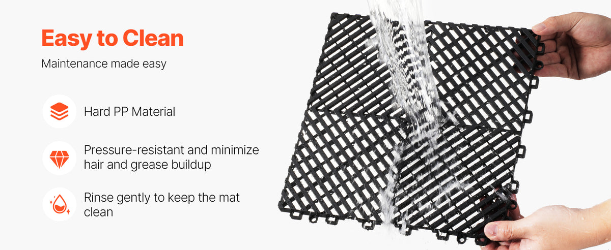 A hand is rinsing a black interlocking drainage mat with water.