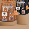 A brown capybara style school backpack with multiple compartments and padded features is shown next to a black version.